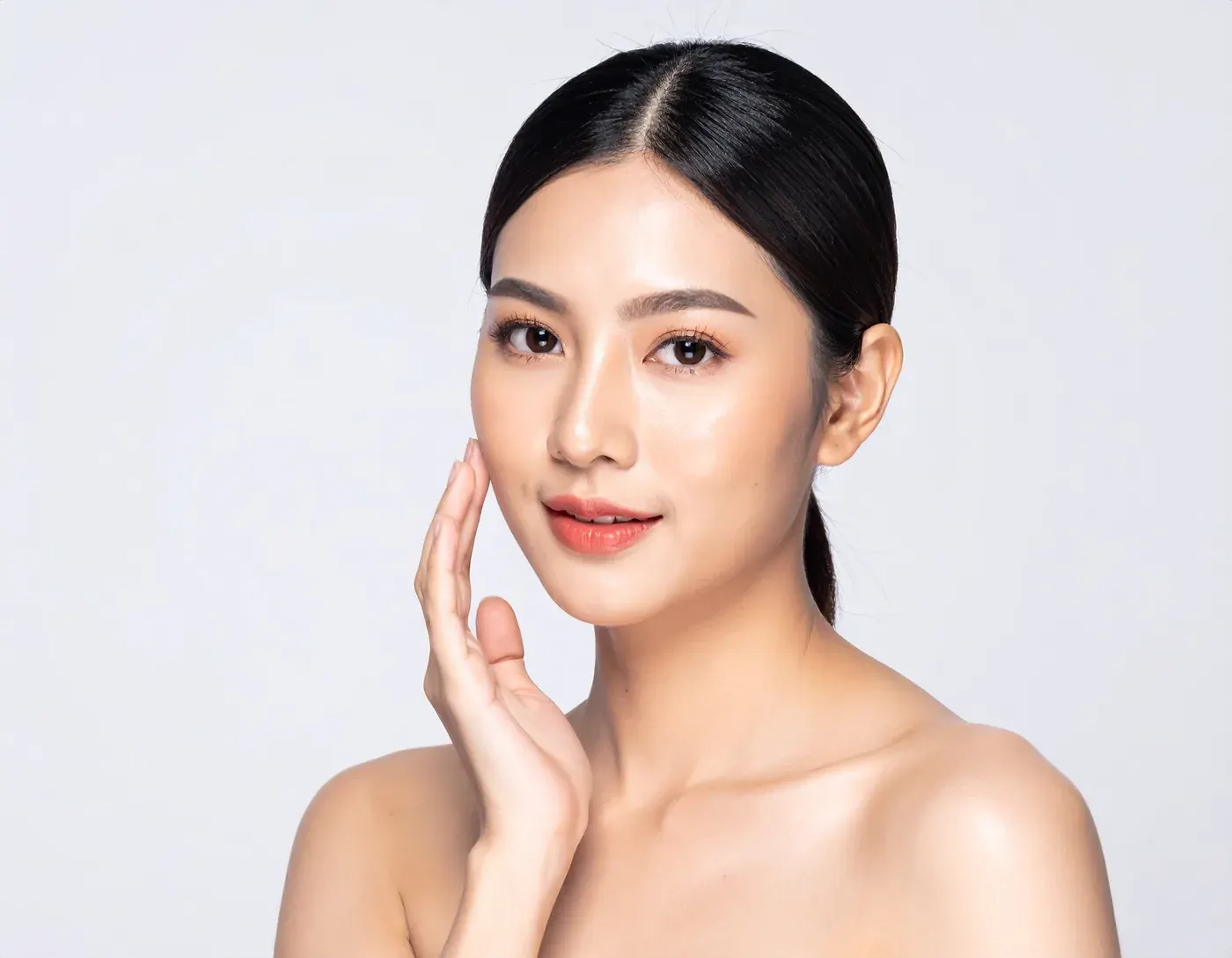 Cô gái chạm tay lên má, da mặt sạch mụn